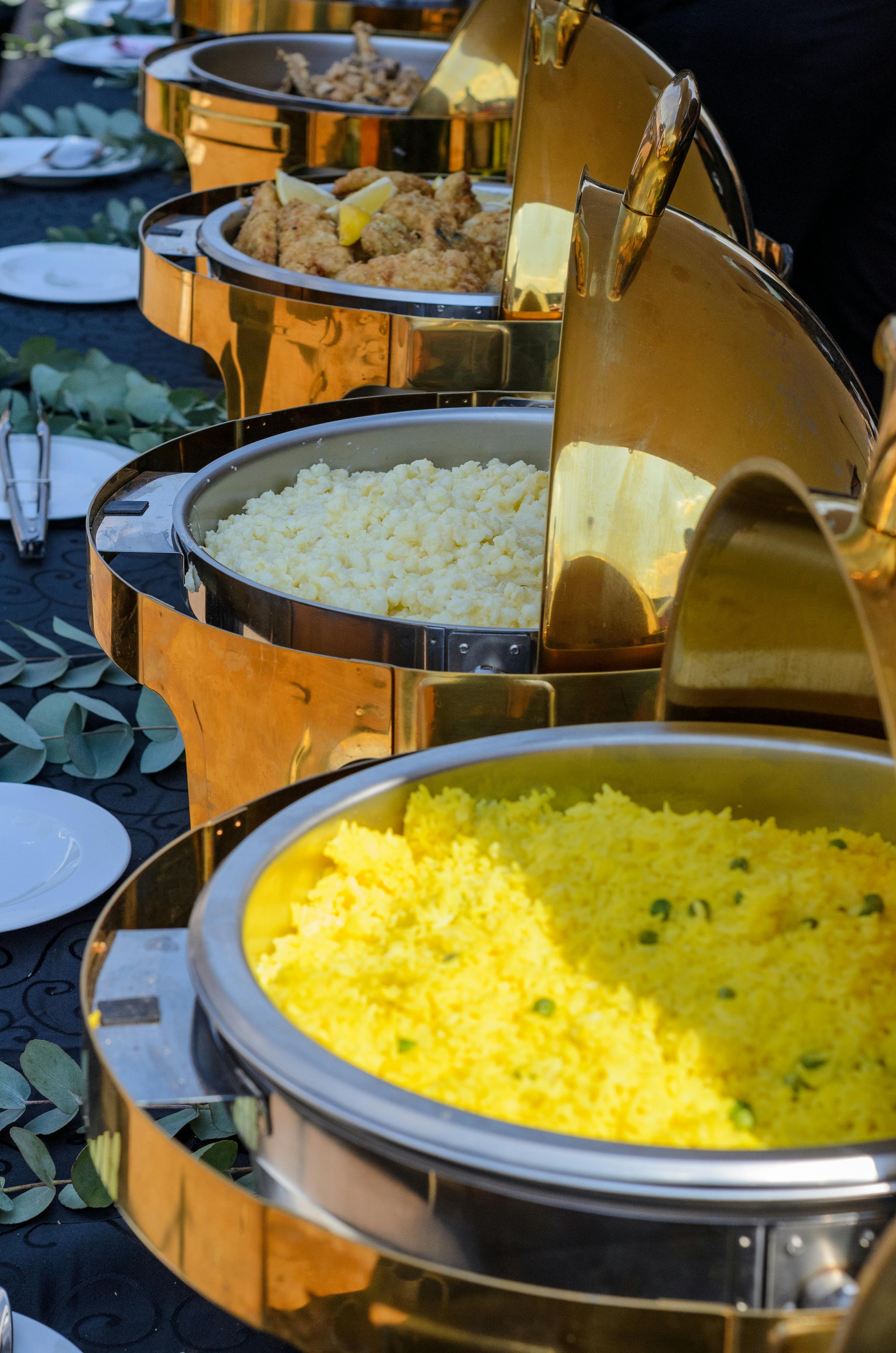 A vibrant buffet spread featuring yellow rice and various options in elegant chafing dishes.